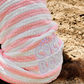 Pink and white poncho towel on a dog with Coco+Bondi branding on the beach